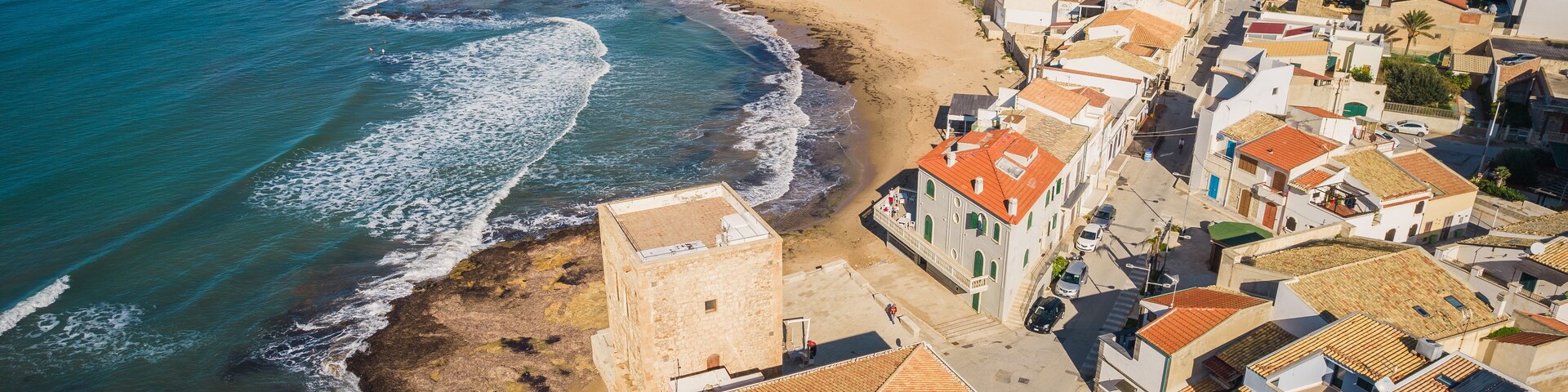 A coastal town with a beach, buildings, and the sea.