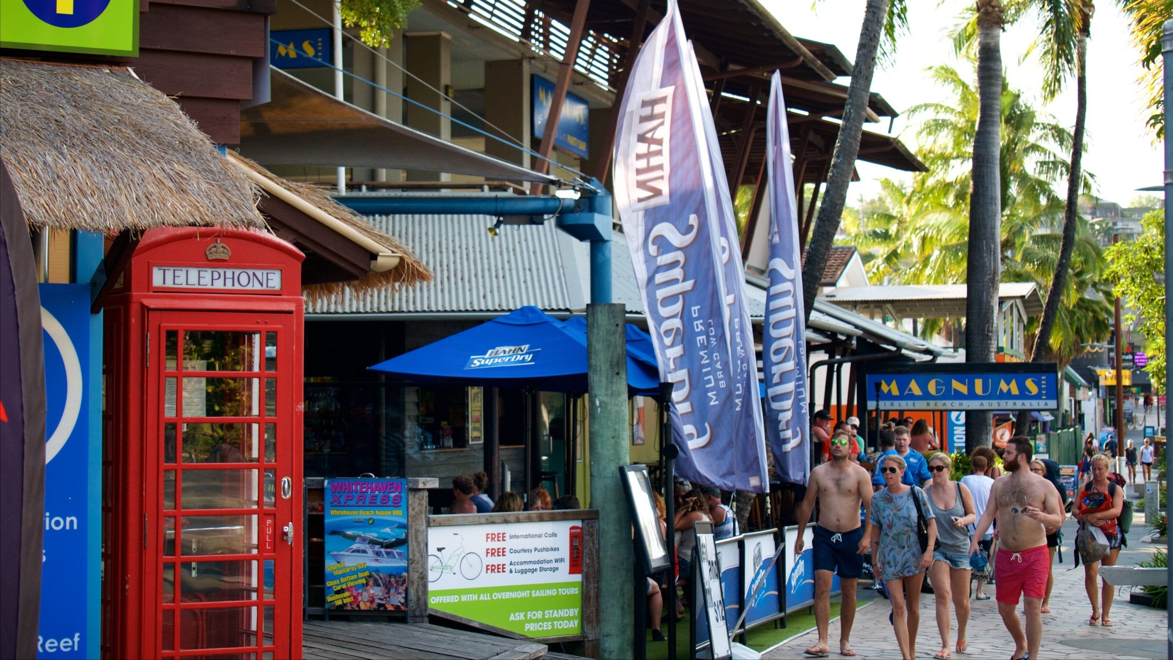 Uma cabine telefônica vermelha, um guarda-chuva azul e bandeiras com texto.