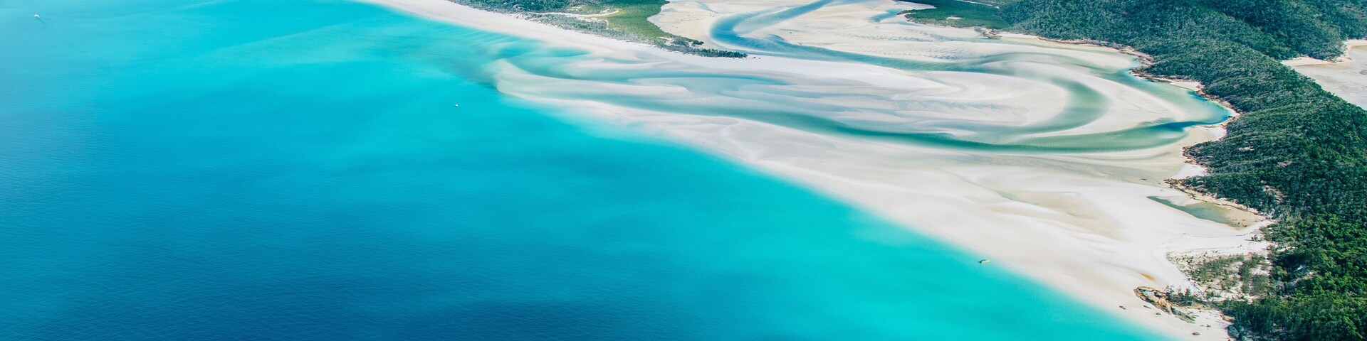 Un paisaje costero con aguas turquesas, playas de arena blanca y colinas verdes exuberantes.