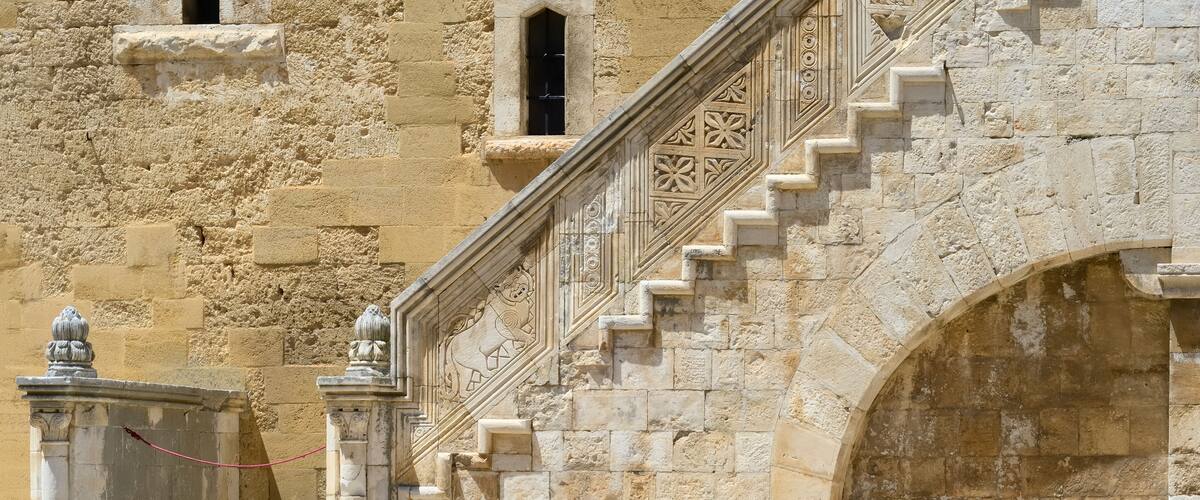 A stone staircase with intricate carvings and a large arched doorway.