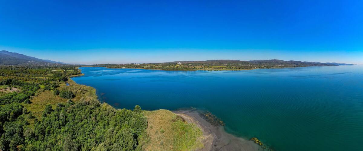A large lake surrounded by mountains and dense forests.