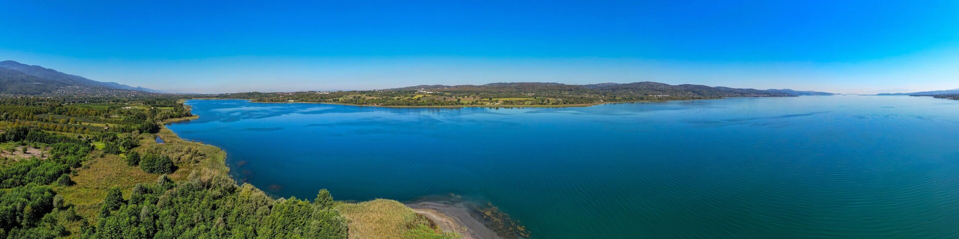 A large lake surrounded by mountains and dense forests.