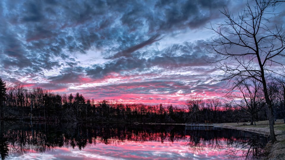 A sunset over a lake with a forest reflection.