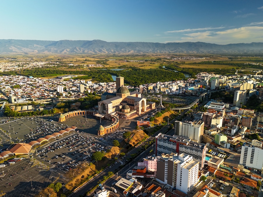 aerial view of the Basilica of the National Shrine of Our Lady Aparecida in Brazil during sunrise with mountains and greenery at distance