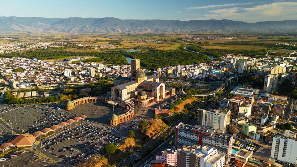 aerial view of the Basilica of the National Shrine of Our Lady Aparecida in Brazil during sunrise with mountains and greenery at distance