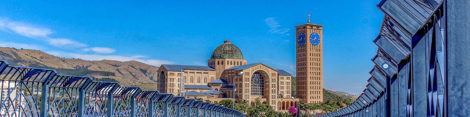 Uma ponte de metal azul com uma torre do relógio e um edifício grande com uma cúpula ao fundo.