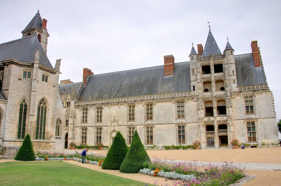 A historic castle with a large courtyard, tall towers, and intricate stonework.
