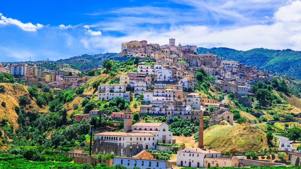 A hillside town with historic buildings and a prominent castle on top.