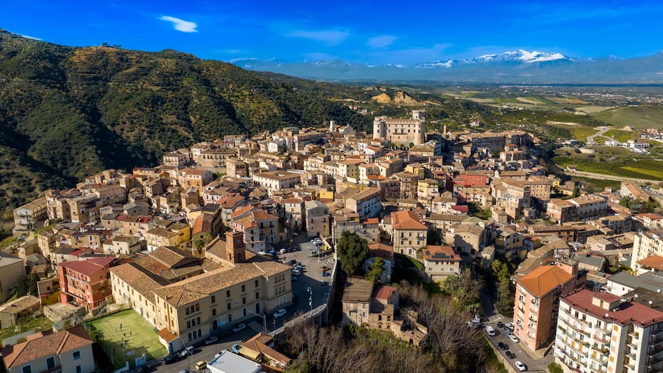 A mountainous town with historic buildings and a castle.