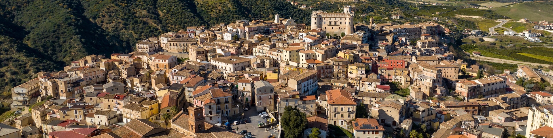 Uma vila montanhosa com edifícios históricos e um castelo.