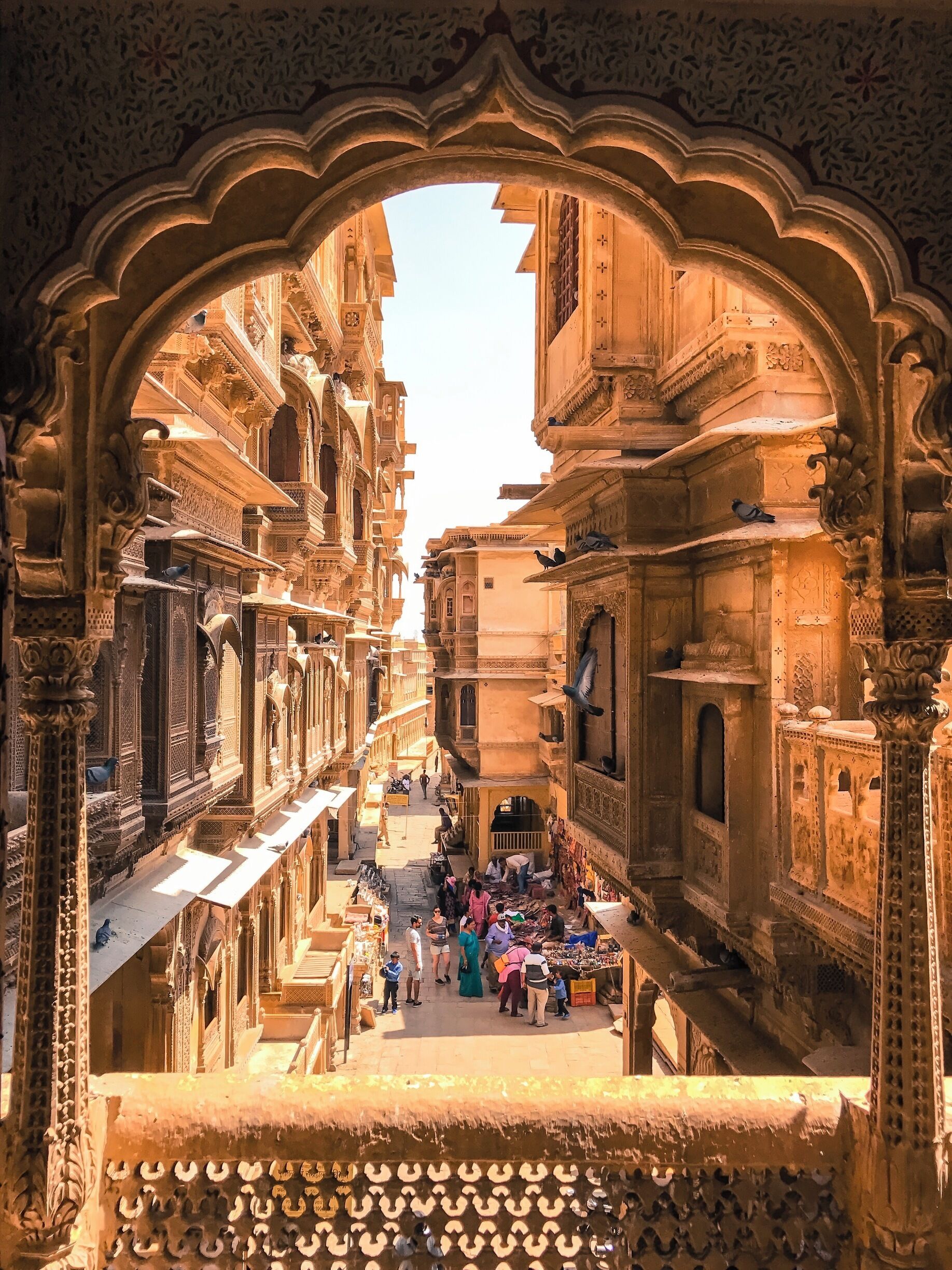 Uma rua estreita ladeada por edifícios ornamentados com esculturas e arcos detalhados.