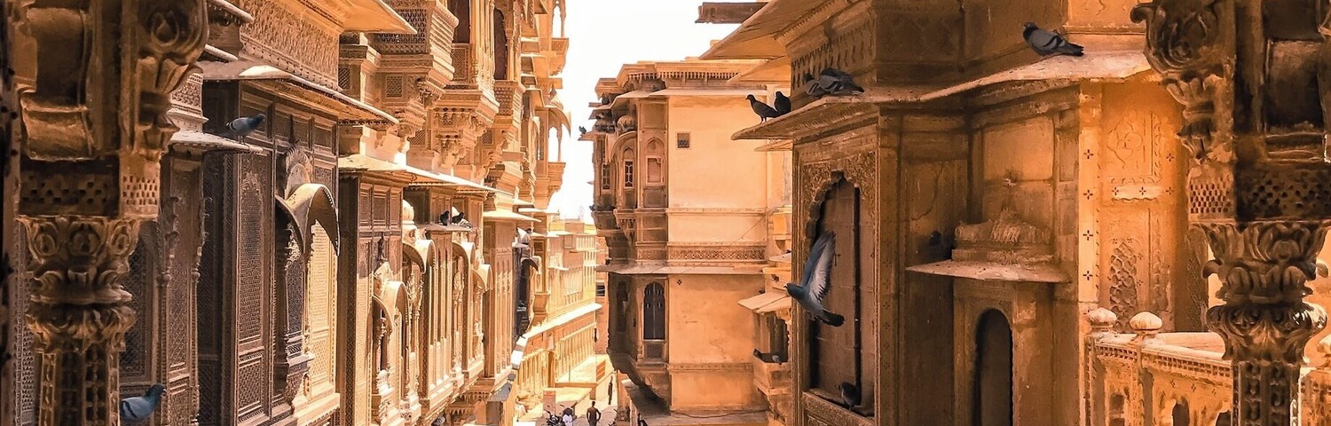 Uma rua estreita ladeada por edifícios ornamentados com esculturas e arcos detalhados.