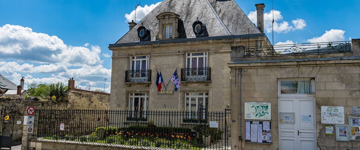A historic building with a stone facade, a steeply pitched roof, and a balcony.