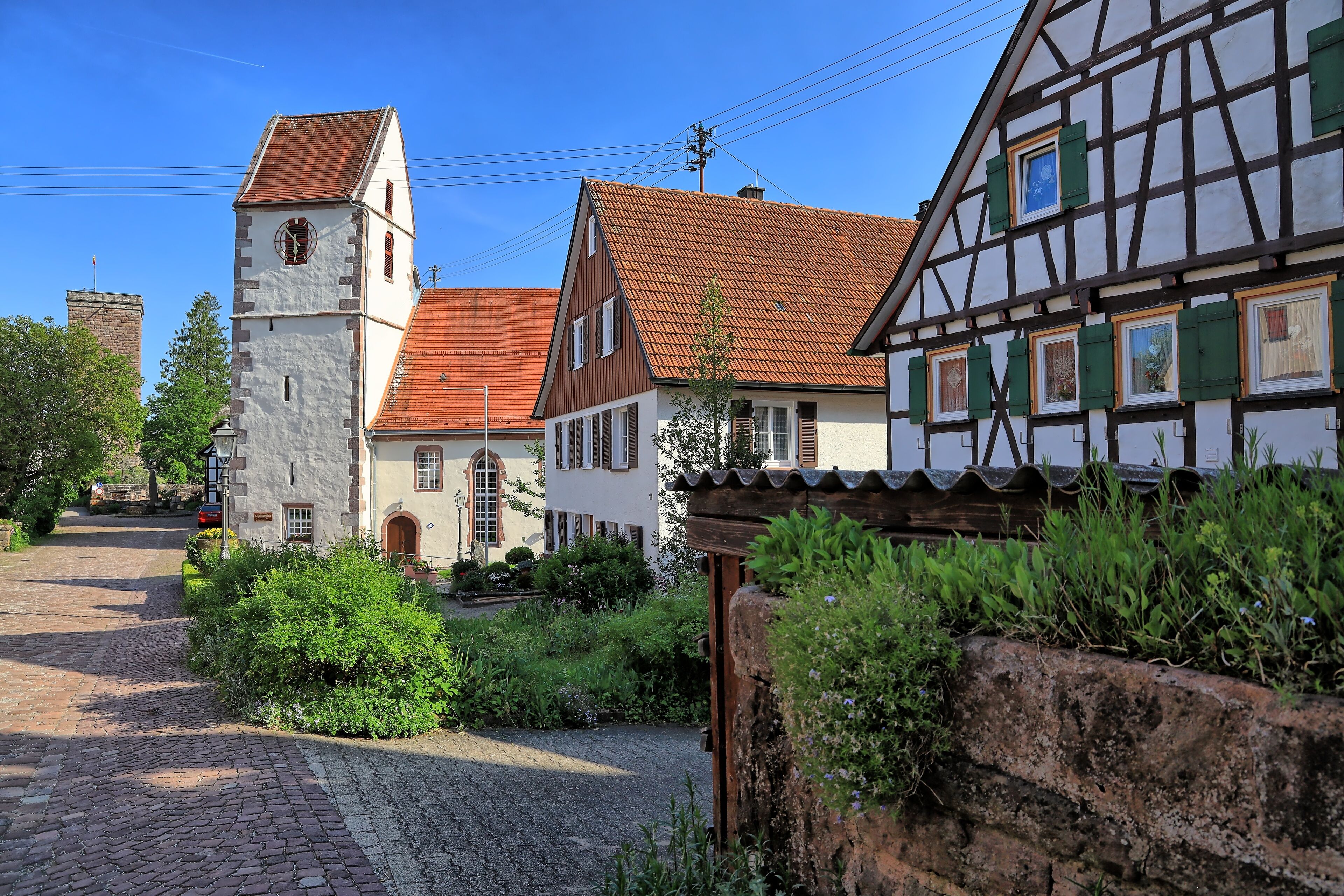 A traditional European village with a church, cobblestone street, and half-timbered houses.