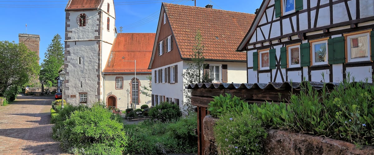 A traditional European village with a church, cobblestone street, and half-timbered houses.
