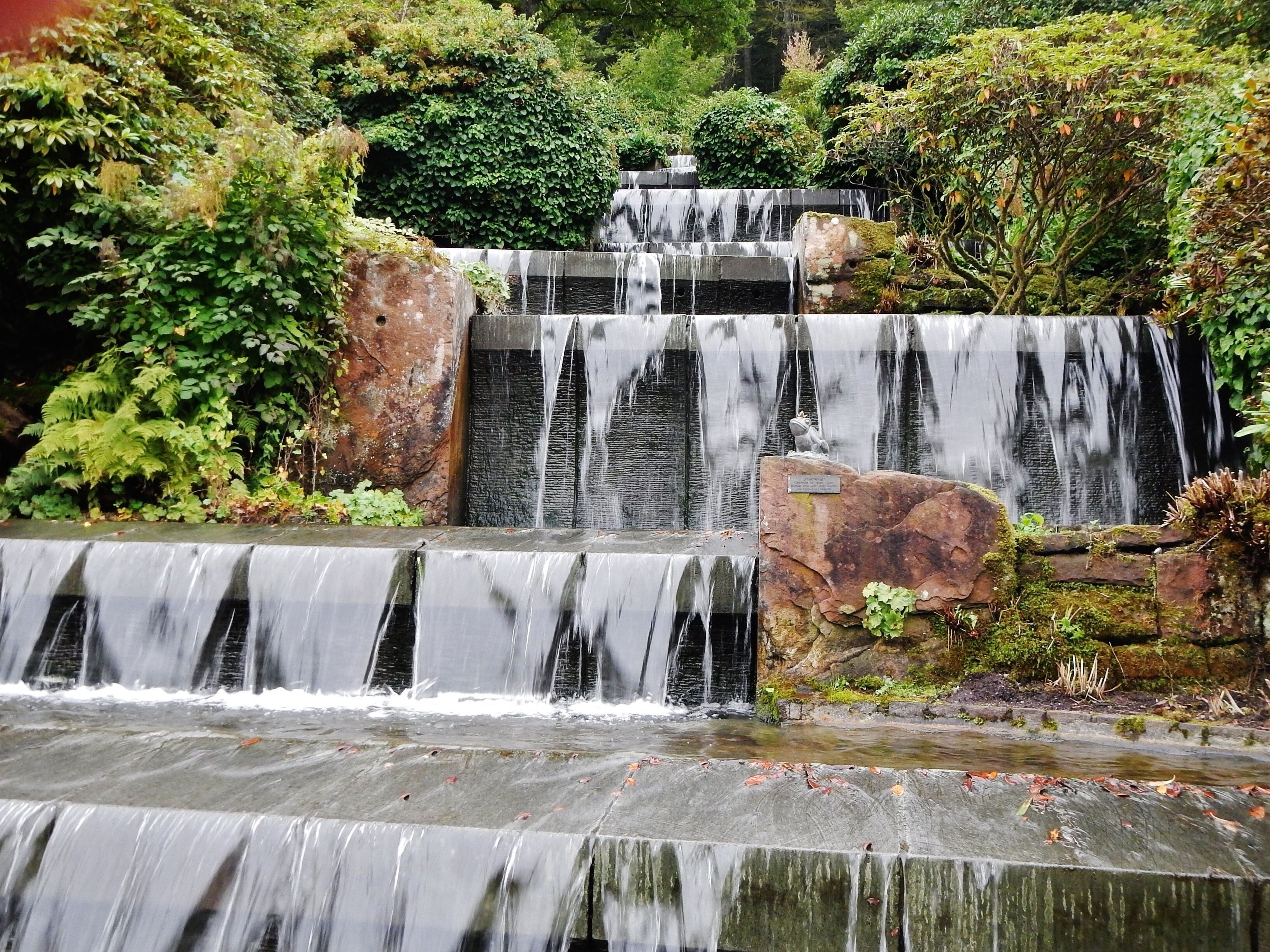 A multi-tiered waterfall cascading over stone steps surrounded by lush greenery.