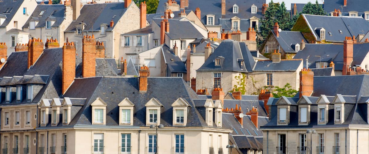 A densely packed urban area with historic buildings featuring steeply pitched roofs and chimneys.