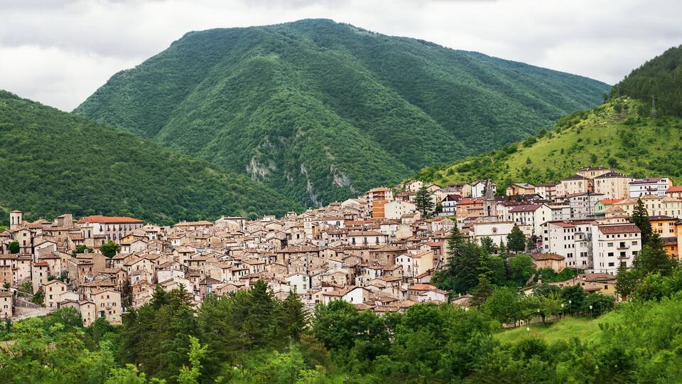 A hillside town with historic buildings nestled among lush green mountains.