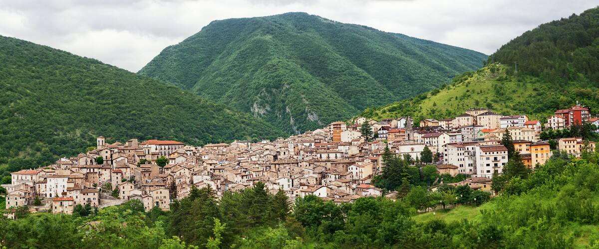 A hillside town with historic buildings nestled among lush green mountains.