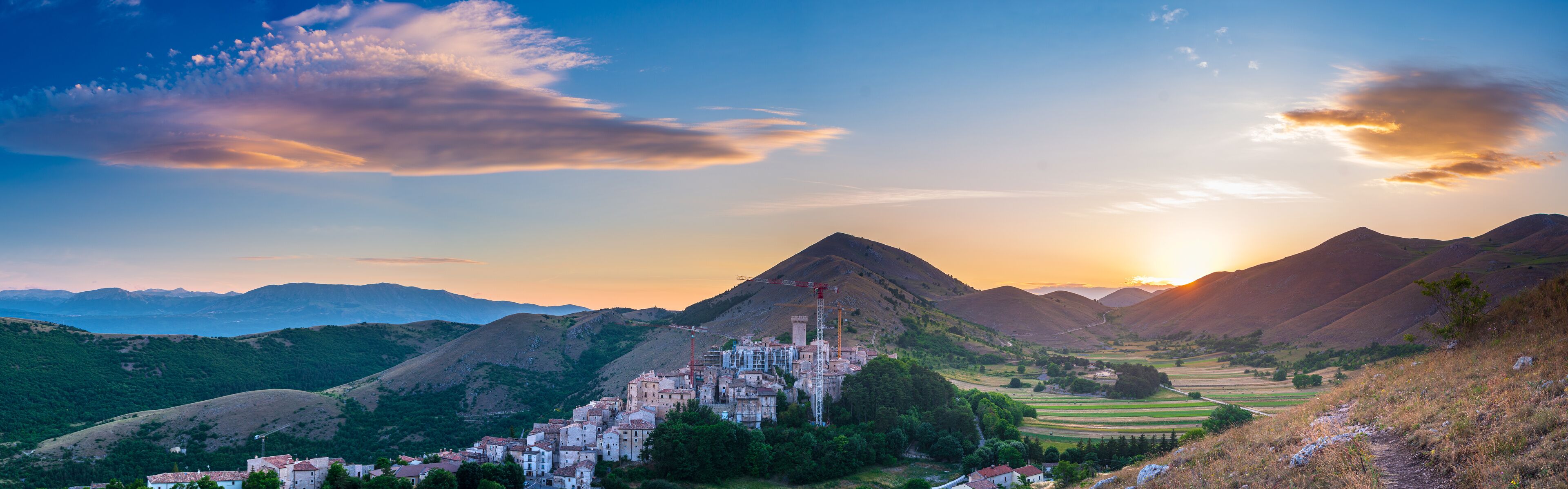 Sunset over medieval village perched on hill top, Santo Stefano di Sessanio, Abruzzo, Italy. Romantic sky and clouds above mountains landscape, tourism destination.