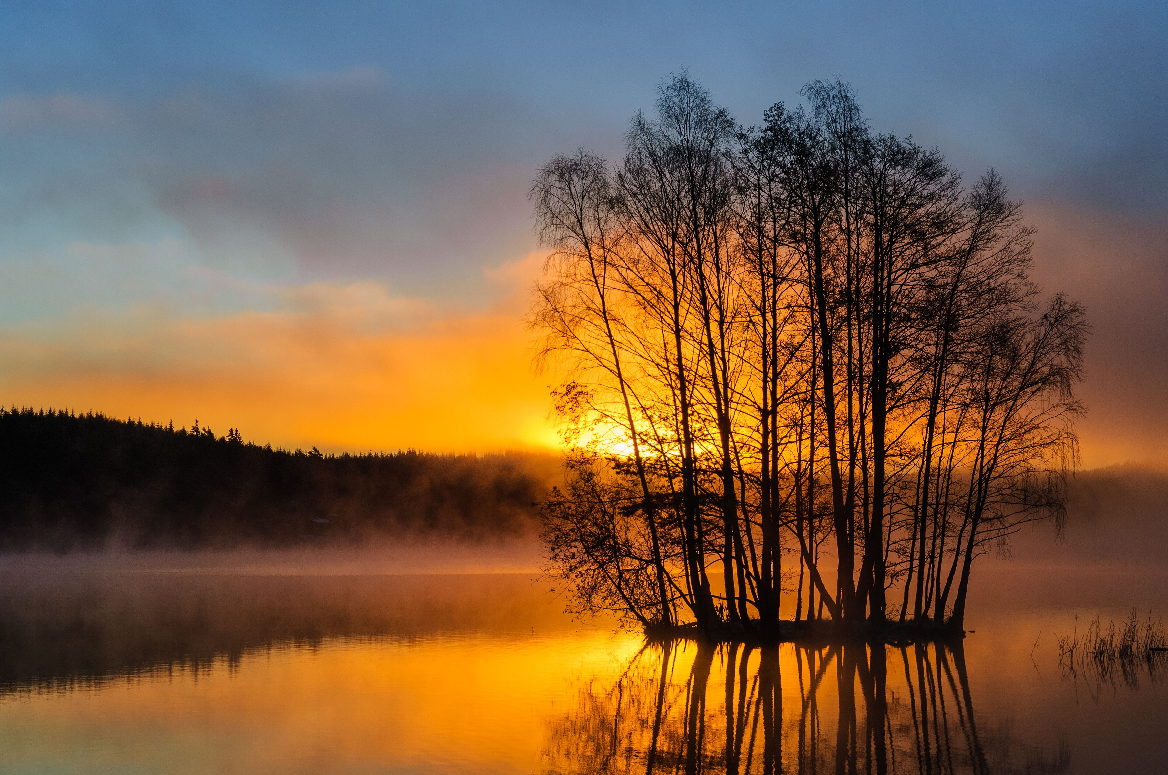 A sunset over a calm lake with a tree-covered island.