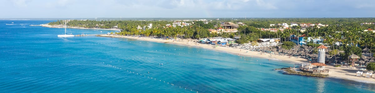 A coastal town with a beach, palm trees, and a lighthouse.