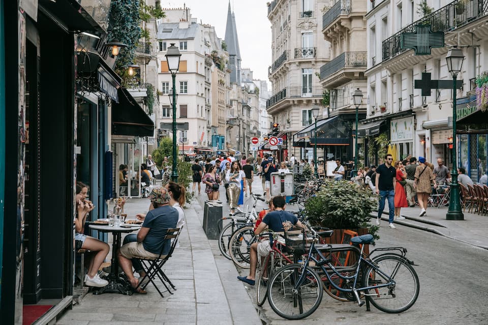 A bustling street with cafes, bicycles, and pedestrians.