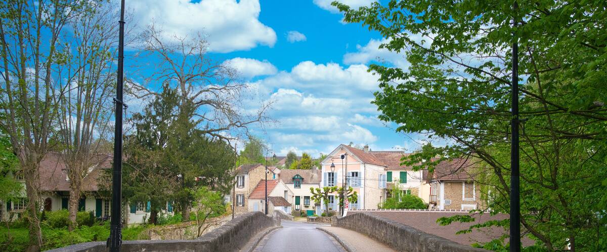A narrow street named L'Yerres with stone walls on either side, leading to a row of traditional houses with red roofs.