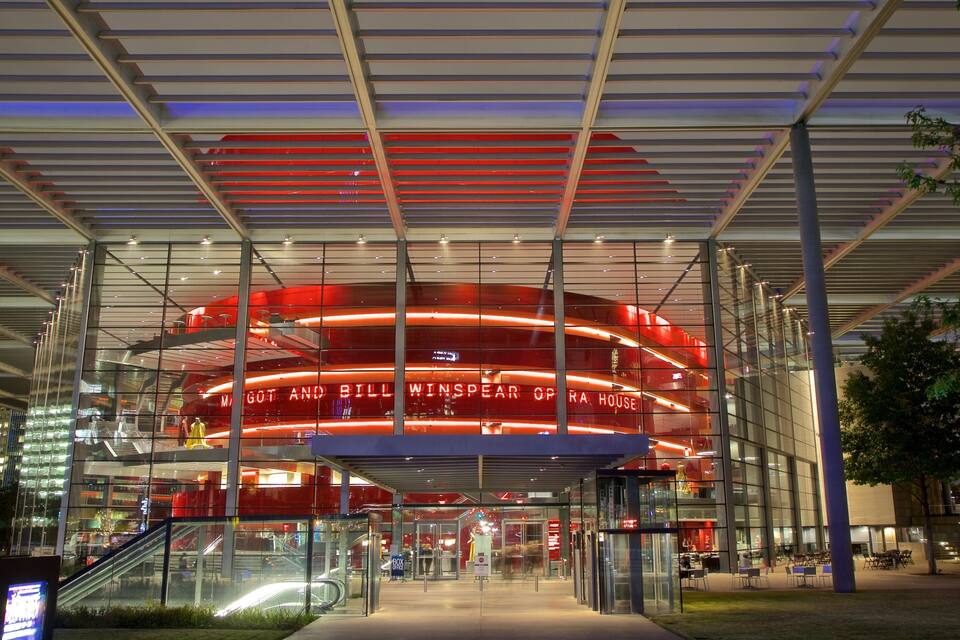 Een modern gebouw met een glazen gevel en een rood verlicht interieur.