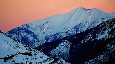 A snow-covered mountain range with a winding road at the base.