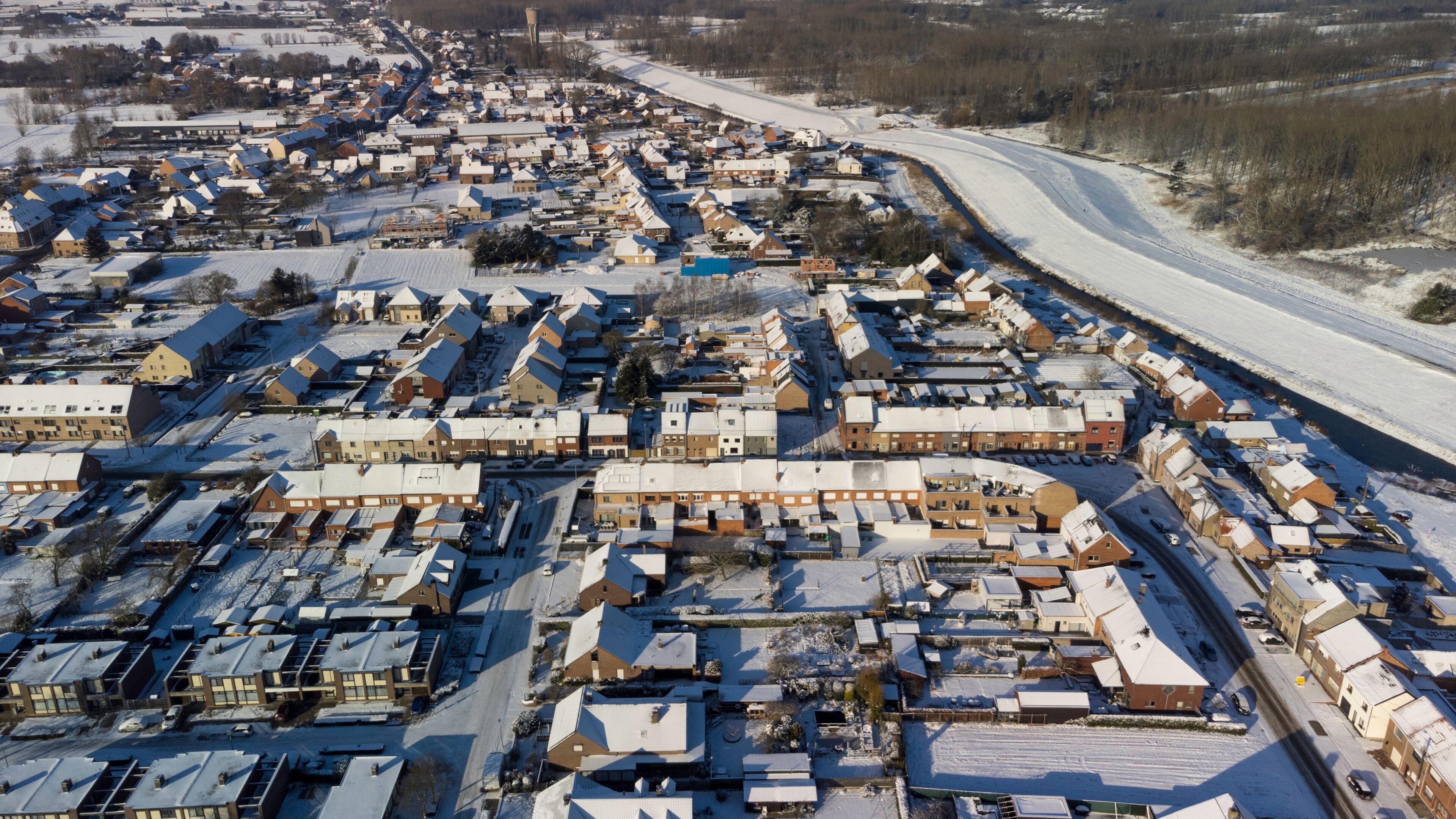 A snow-covered residential area with houses and a winding road.