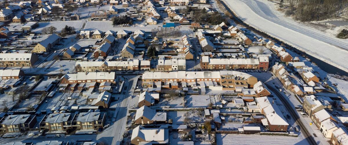 A snow-covered residential area with houses and a winding road.