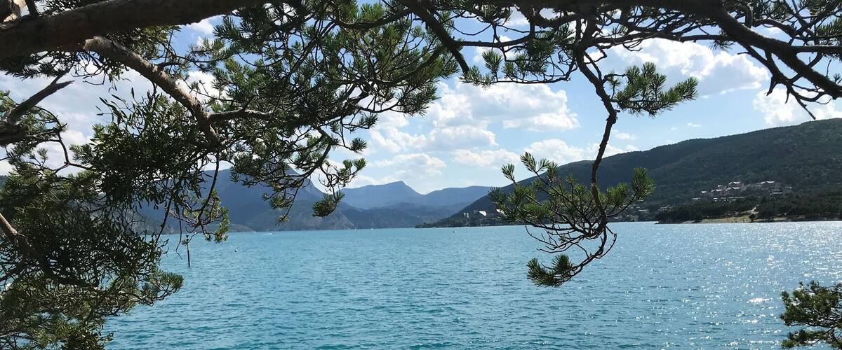 A clear lake surrounded by mountains and pine trees.