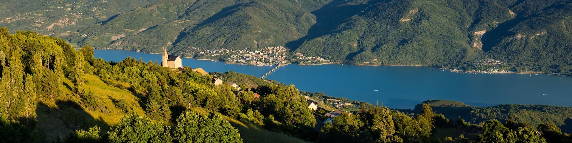 A mountainous landscape with a lake, a church, and a small town.