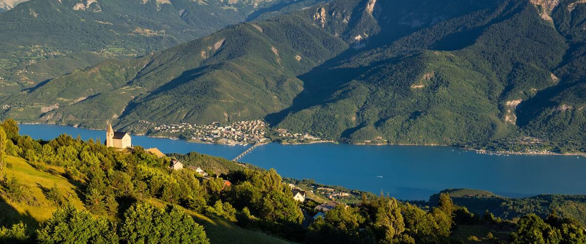 A mountainous landscape with a lake, a church, and a small town.