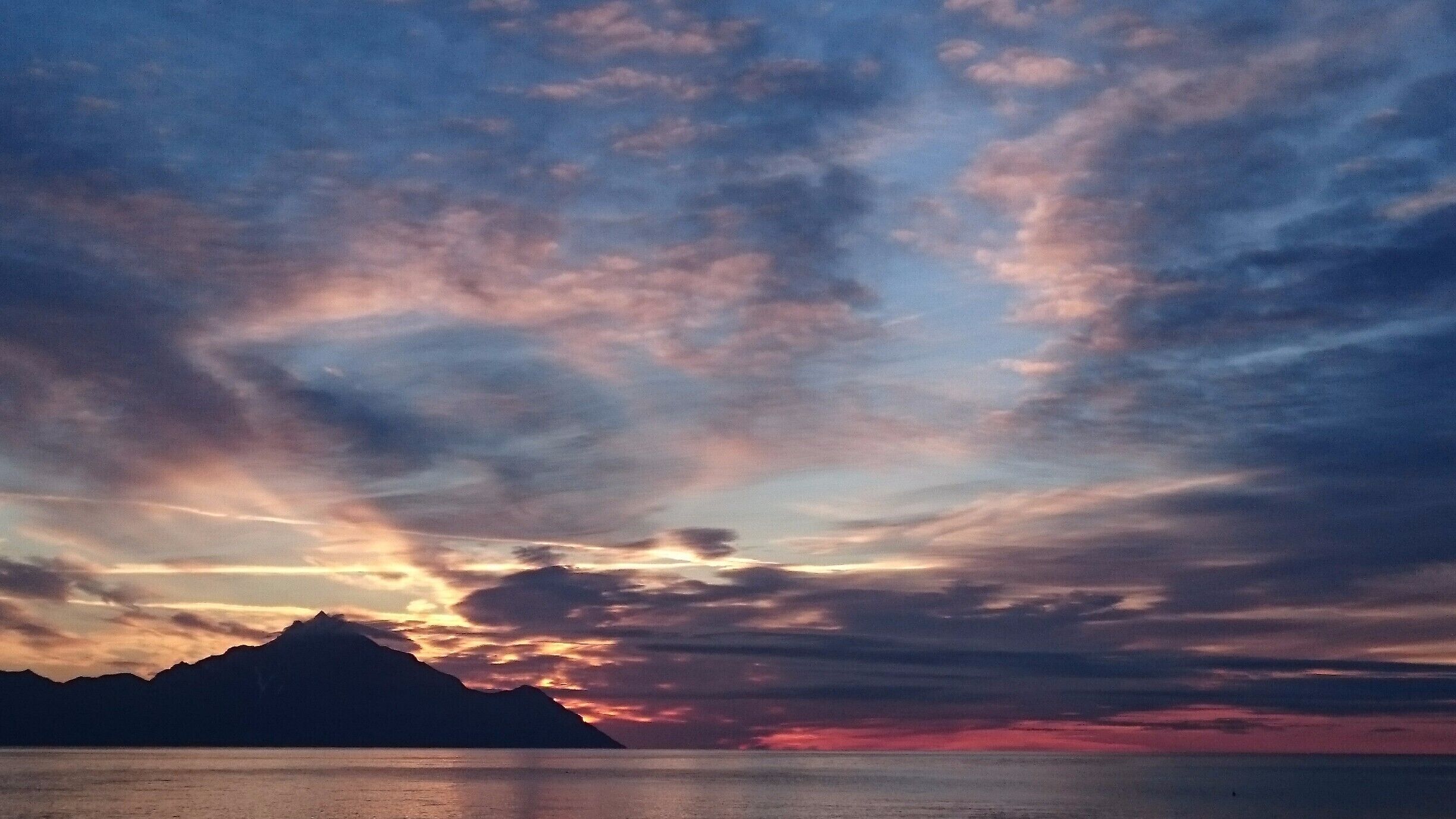 Sunrise from the beach of Sarti, Halkidiki, where you can see mount Athos. 
If you come in April, the town is almost desert and you can sleep freely on the beach. 