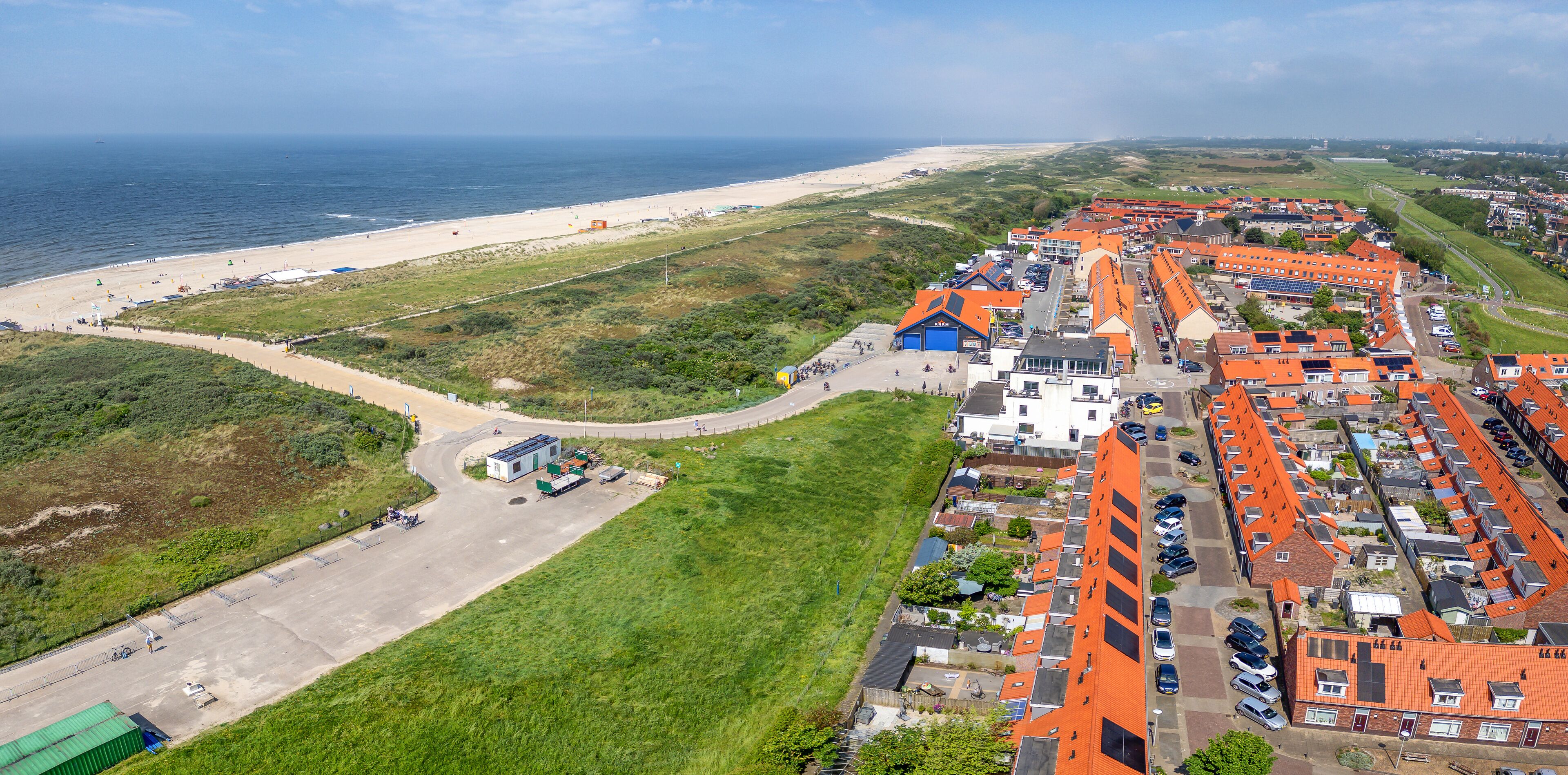 The coastal town of Ter Heijde aan Zee features a blend of green fields, sandy beaches, and vibrant rooftops 