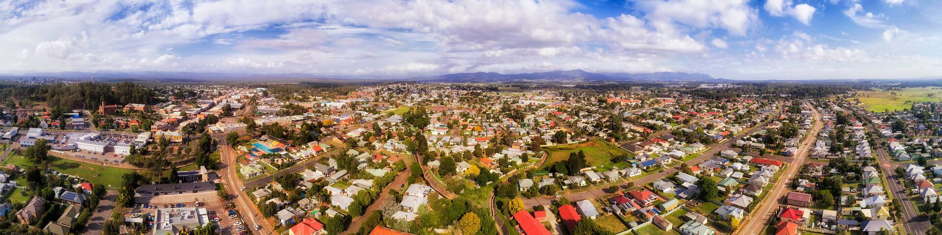 A panoramic view of a town with a mix of residential houses, roads, and a large industrial area.