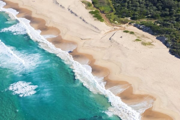 A beach with clear turquoise waters and a sandy shore.