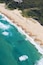 A beach with clear turquoise waters and a sandy shore.