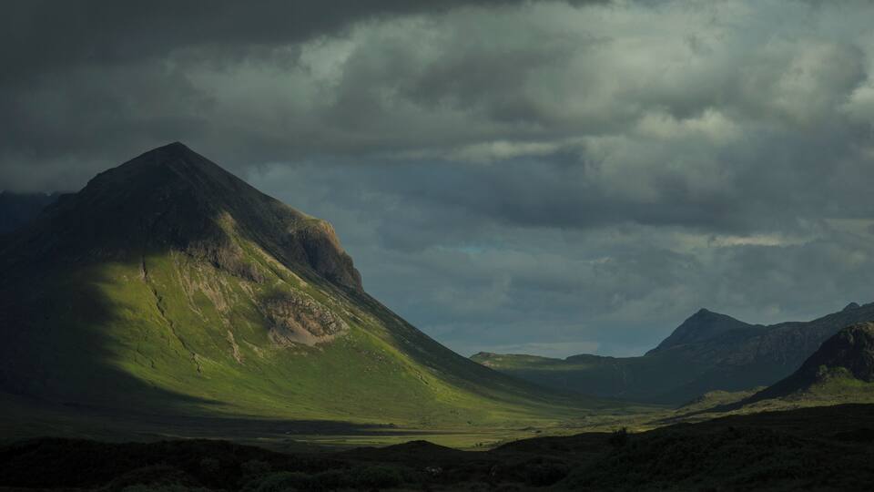 A mountainous landscape with a prominent peak and a valley.