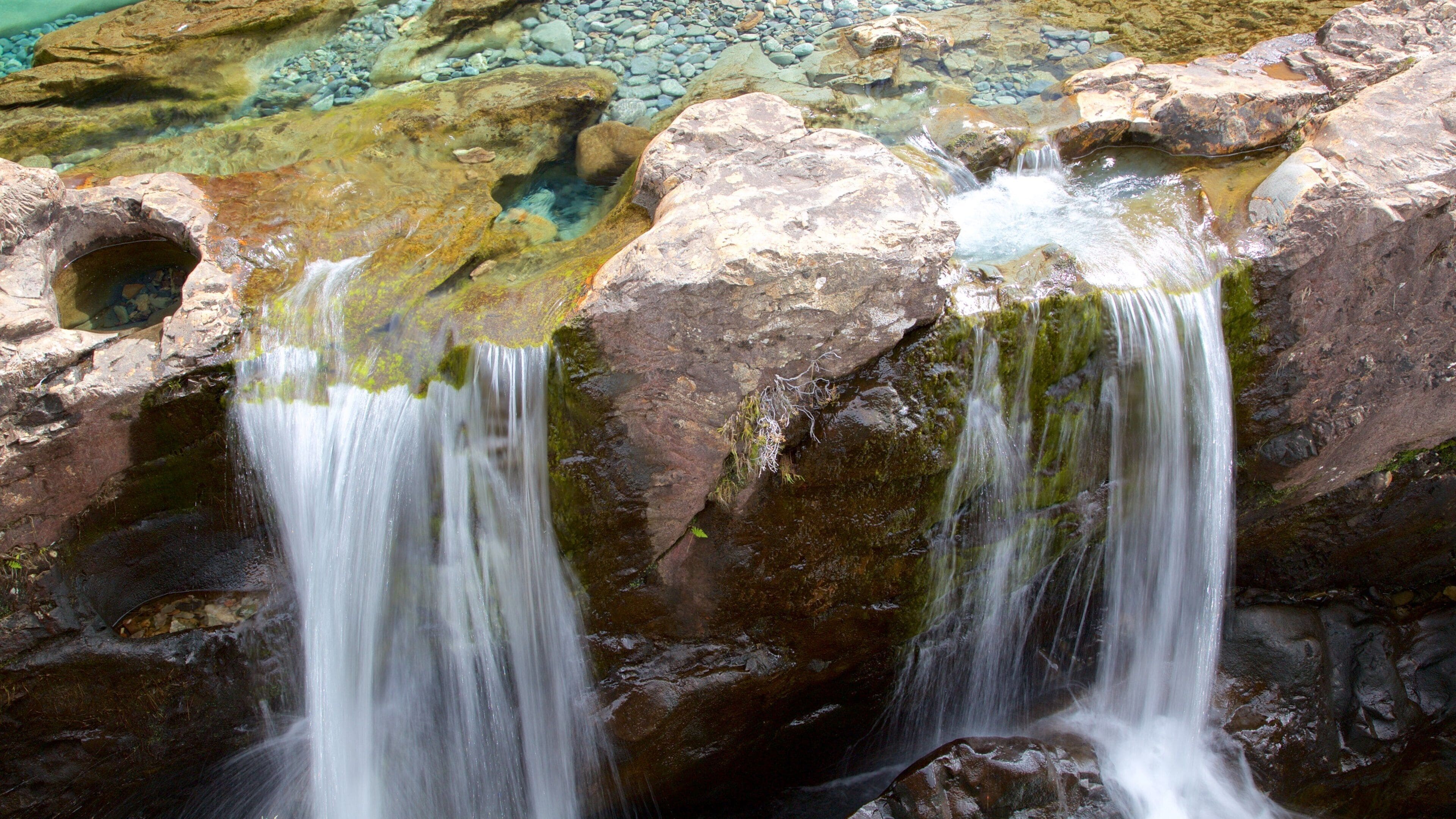 A waterfall cascading over rocks in a clear, shallow pool.
