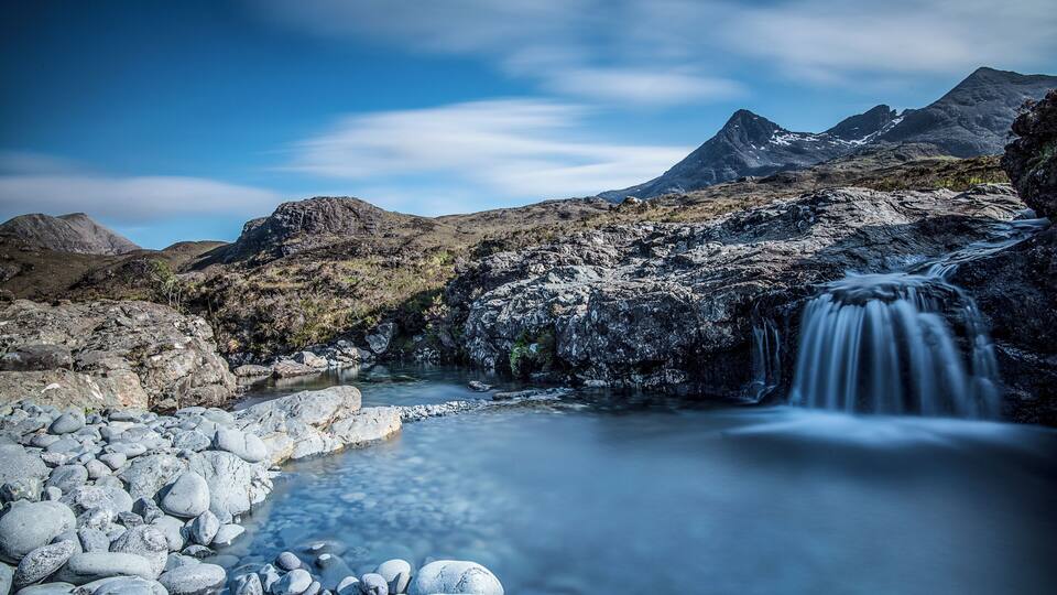 A mountainous landscape with a clear stream flowing over rocks.