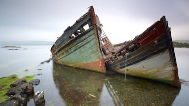 Two sunken ships on a rocky shore with clear water.
