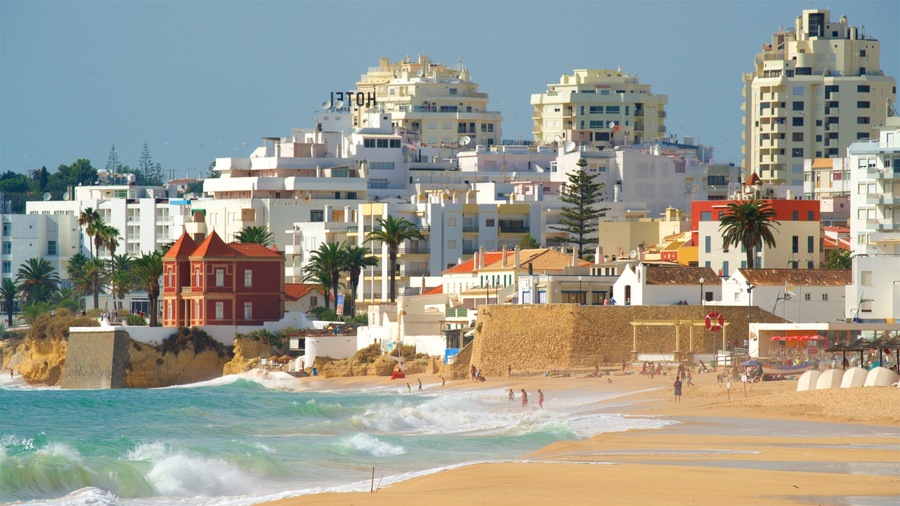 Salgados Beach showing a sandy beach, waves and a city