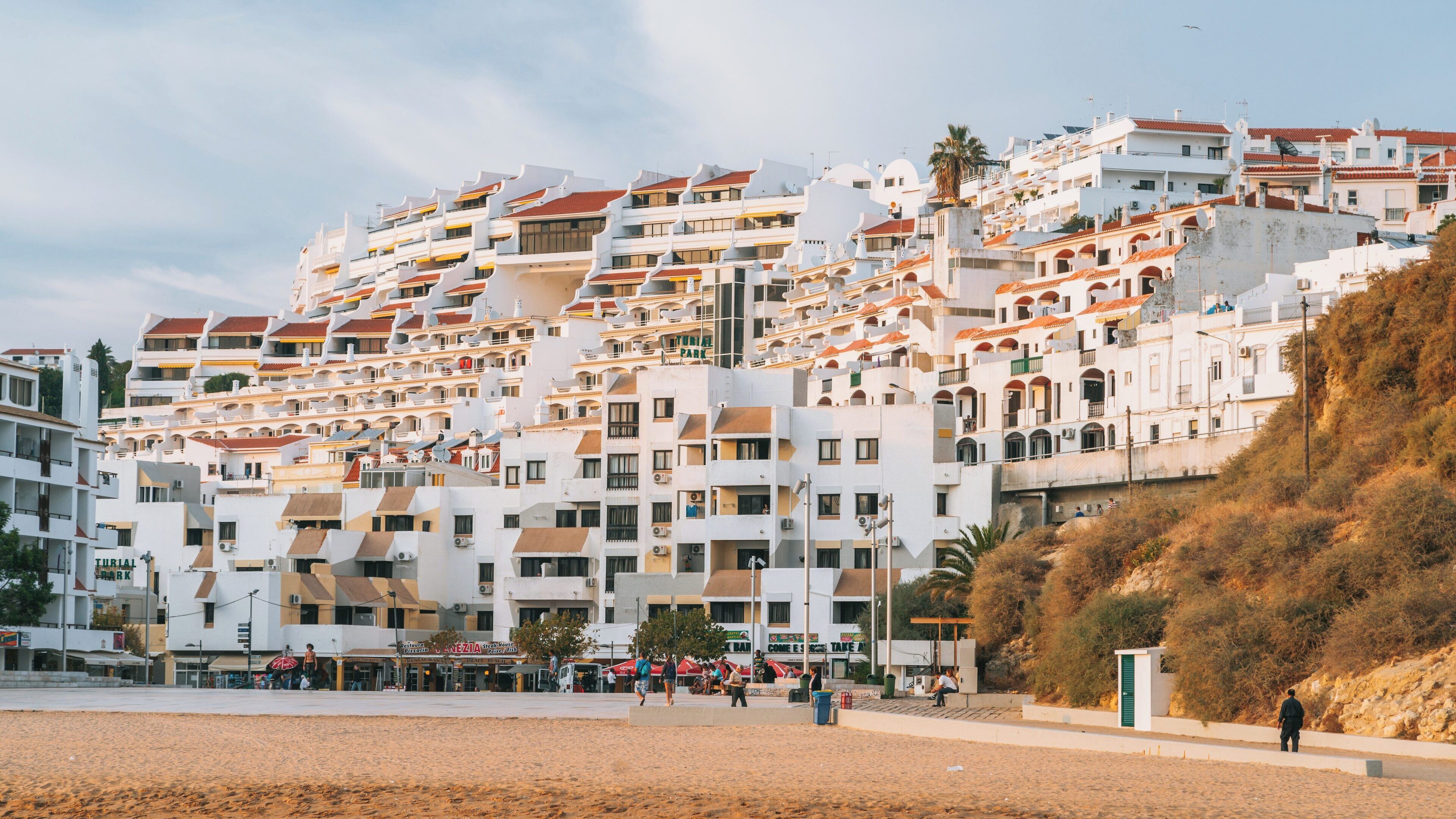 Beautiful coastal view of Salgados Beach with white buildings in Armação de Pêra, Albufeira, Portugal during a warm afternoon