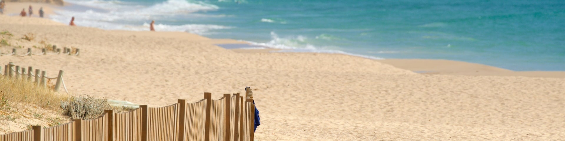 Salgados Beach ofreciendo vista general a la costa y una playa de arena y también un hombre