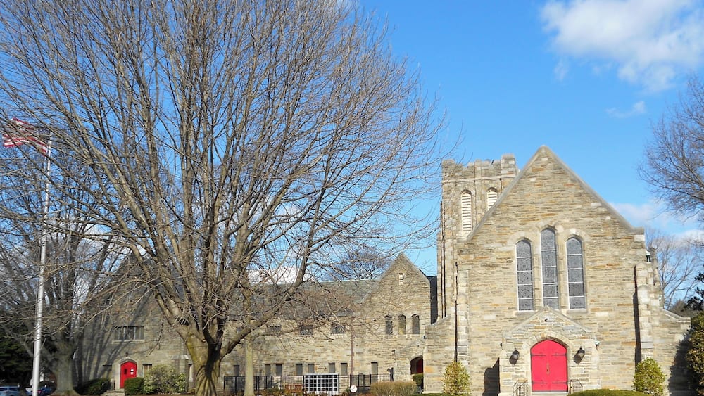 A stone church with a red door and a tall tower.