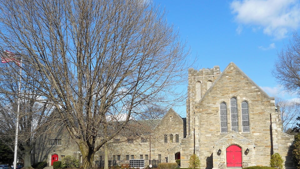 A stone church with a red door and a tall tower.