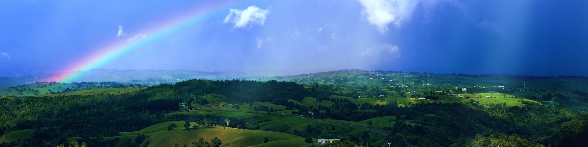 Impressive view at the tropical tableland with a colourful rainbow during rainseason.A heavy tropical rain falling down on the forests and valleys. Millaa Millaa Lookout,Far North Queensland,Australia